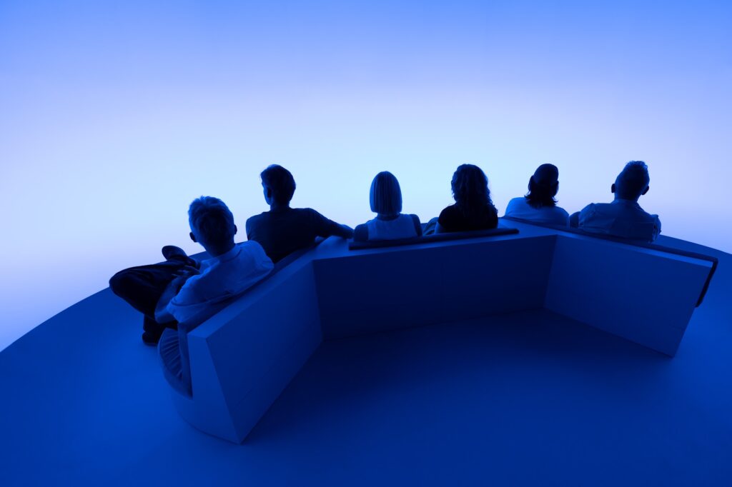 A group reclining on the platform of Chasing the Dot in blue light