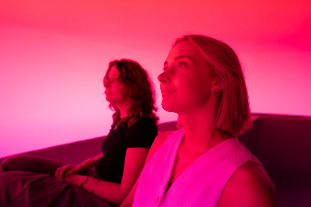 Two visitors lit in pink inside Chasing the Dot