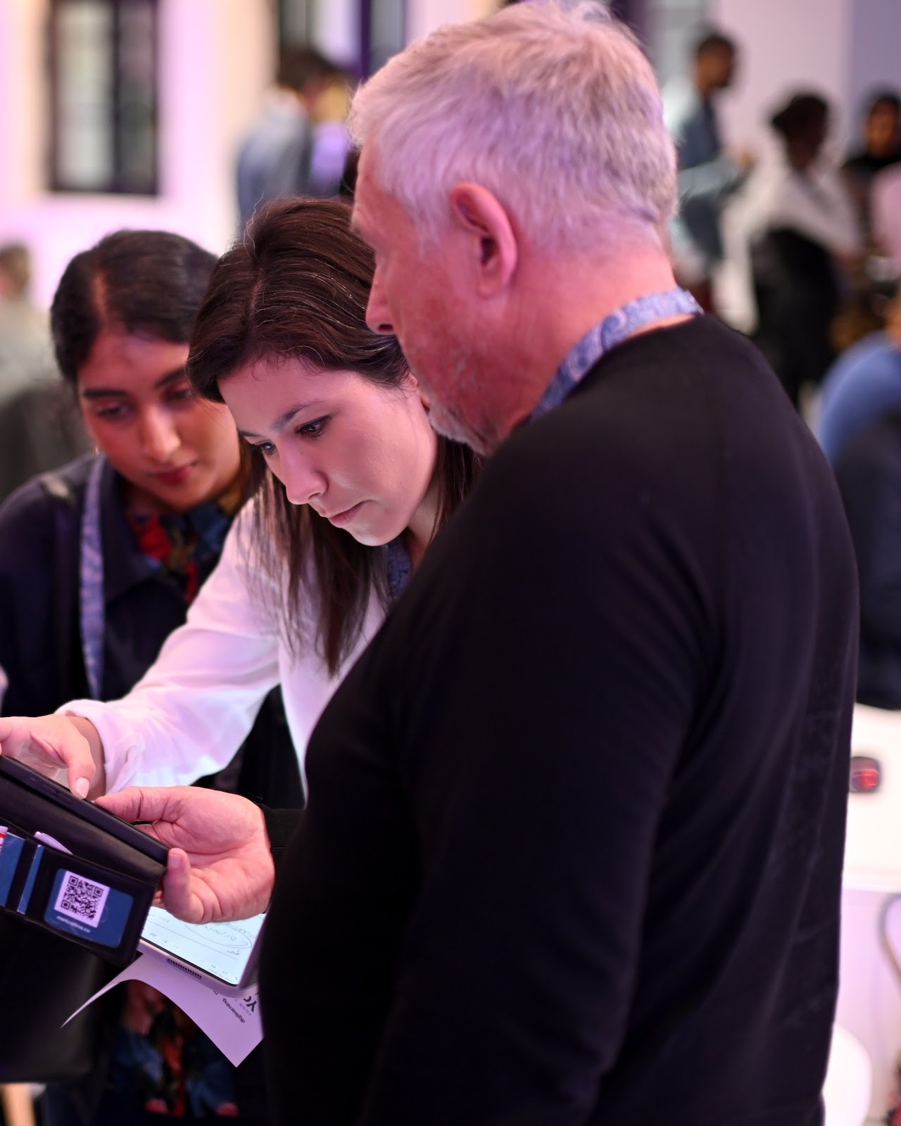 Delegates of different generations look at a phone together between sessions at Future Forum