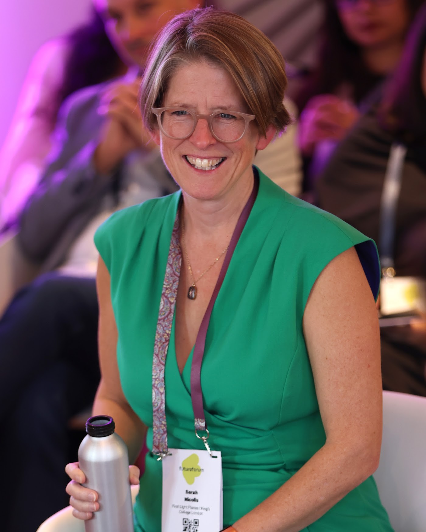 A delegate in a green dress smiles during a session in the Salon at Town Hall