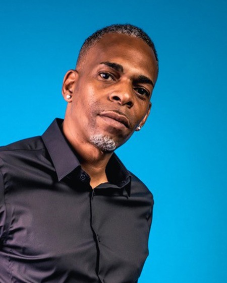 Slim in a black shirt against a blue background