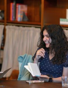 A woman laughing as she writes in a notebook at a table