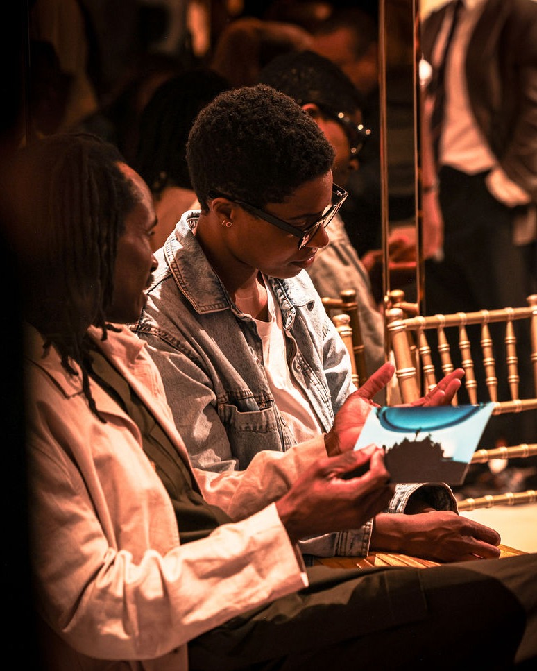 Two guests in the audience, one holding a pitch night card